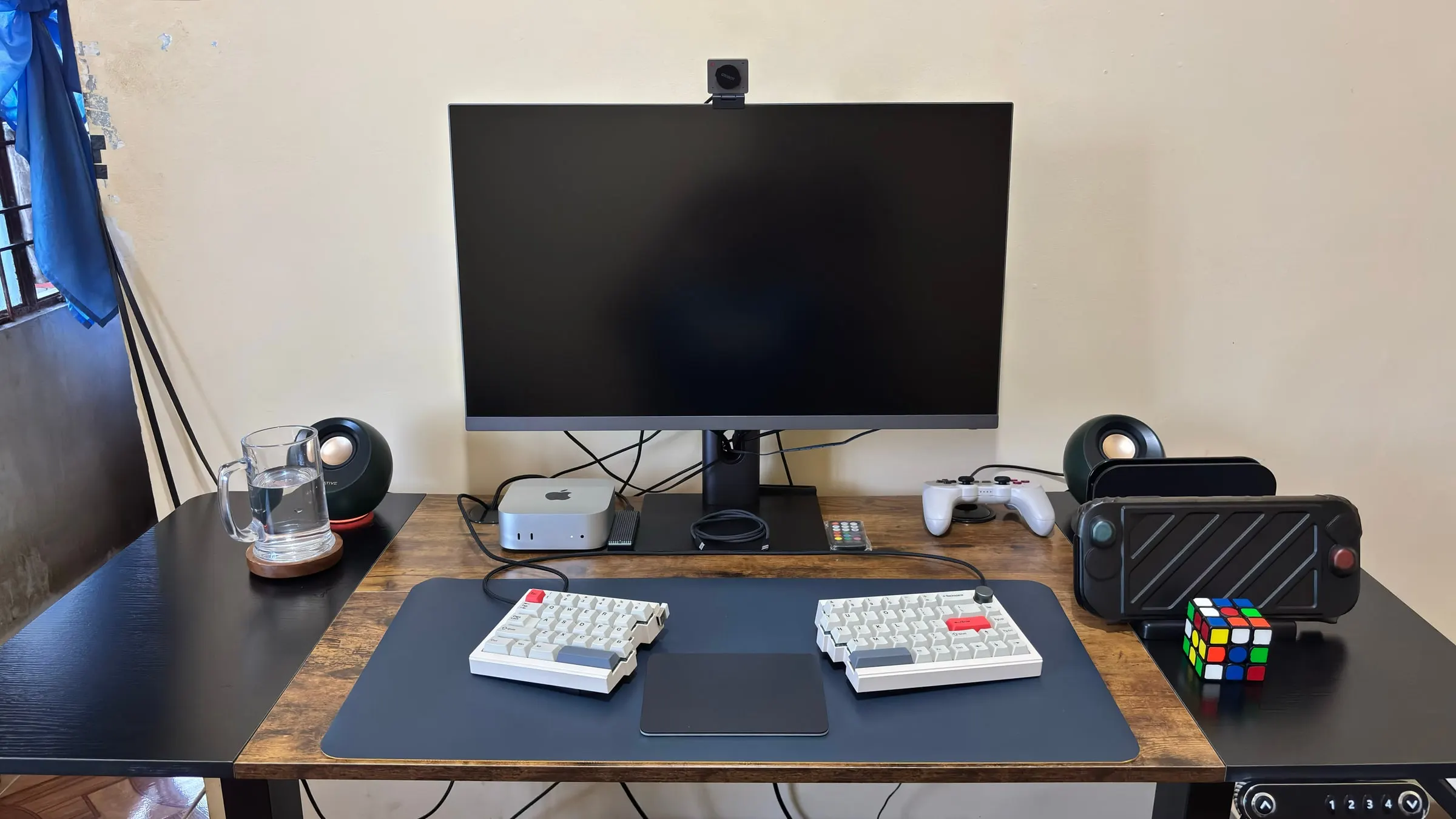 Jonathan's desk setup with an ultrawide display, Mac mini, split keyboard, trackpad, speakers, controller, and Nintendo Switch 2.